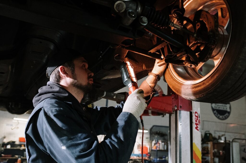 mécanicien examine une voiture par en-dessous